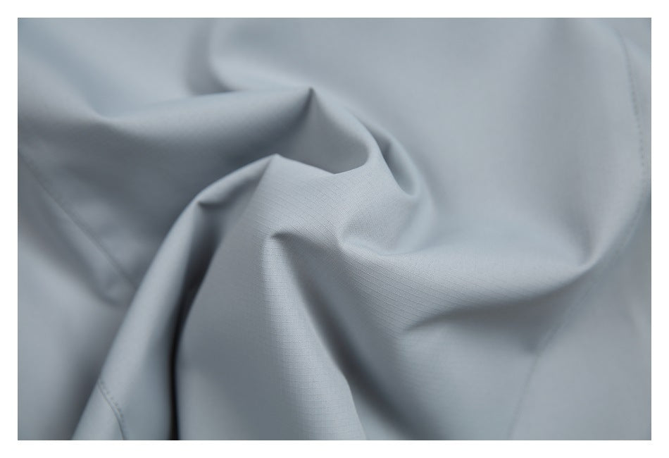 Close-up of softly folded light gray garment fabric with a subtle fine grid texture.
