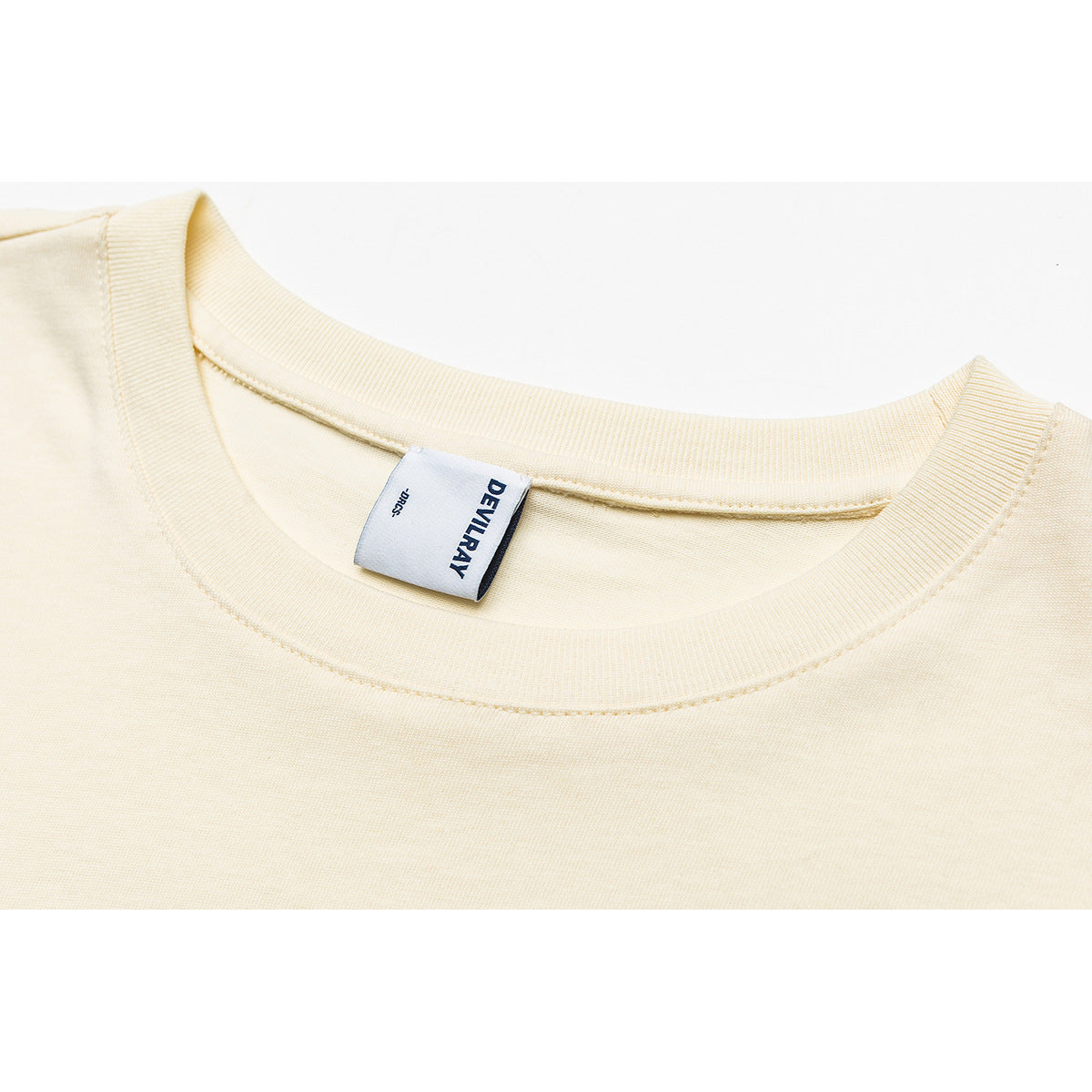 Close-up of an ivory T-shirt crew neck and sewn-in DEVILRAY label.
