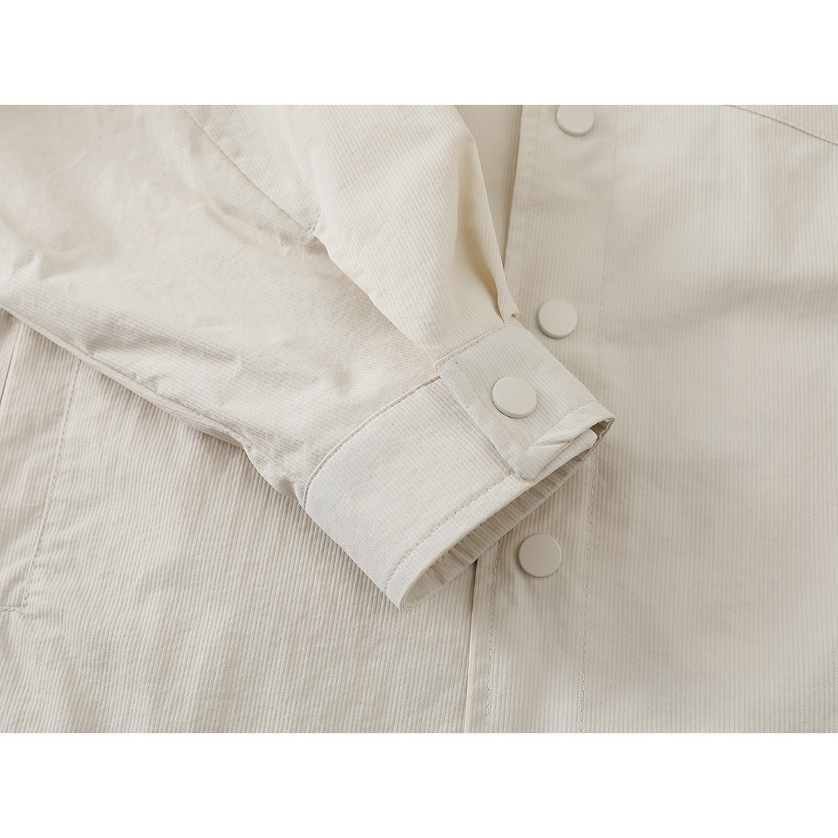 Close-up of the ivory ribbed shirt jacket's buttoned cuff and front placket.