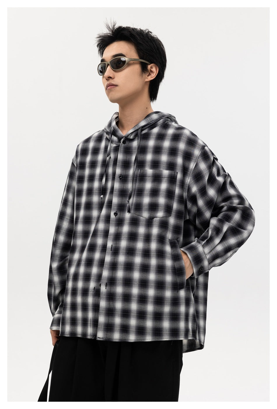 Front view of a model wearing a black-and-white plaid hooded button-up shirt with a chest pocket.