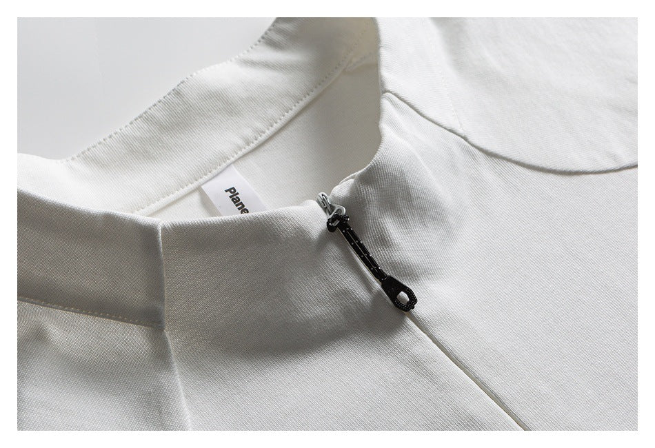 Close-up of the white top's stand collar, neck label, and black zipper pull.