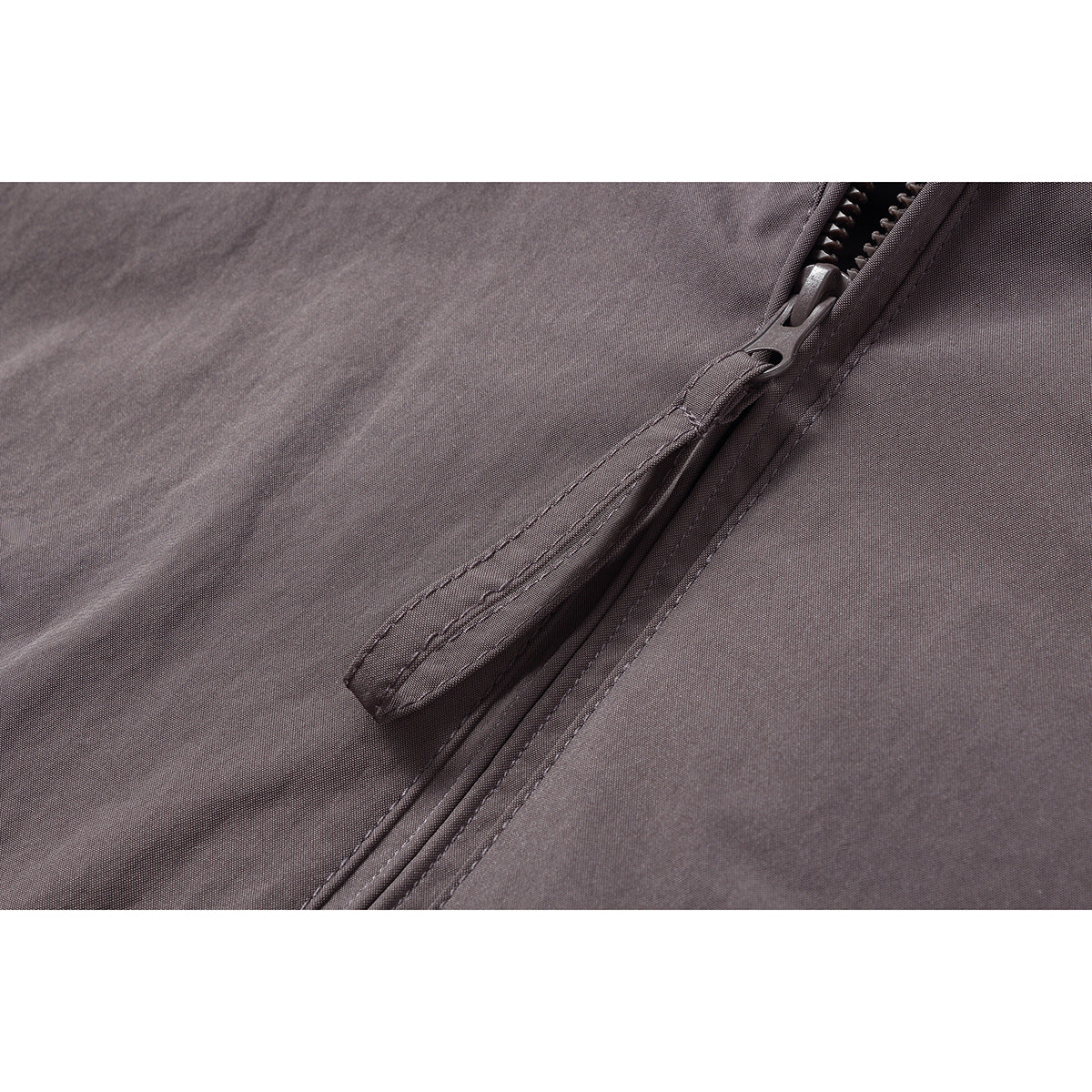 Close-up of a dark gray jacket's front zipper and fabric-covered zipper pull.
