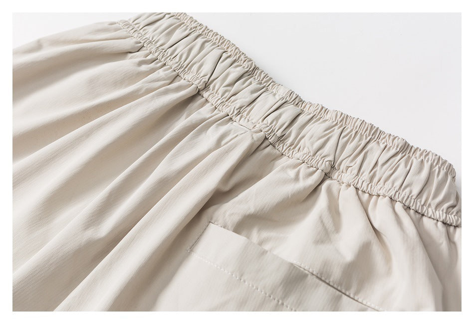 Light beige garment detail showing a gathered elastic waistband and a large stitched pocket.
