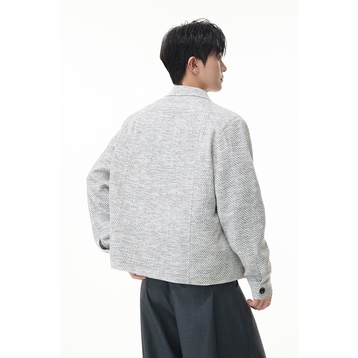 Rear view of a model wearing a light gray textured jacket with a straight hem and buttoned cuffs.