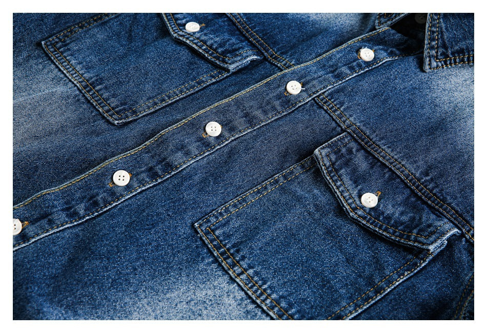 Close-up of a dark blue denim shirt front showing two flap pockets, white buttons, and contrast stitching.