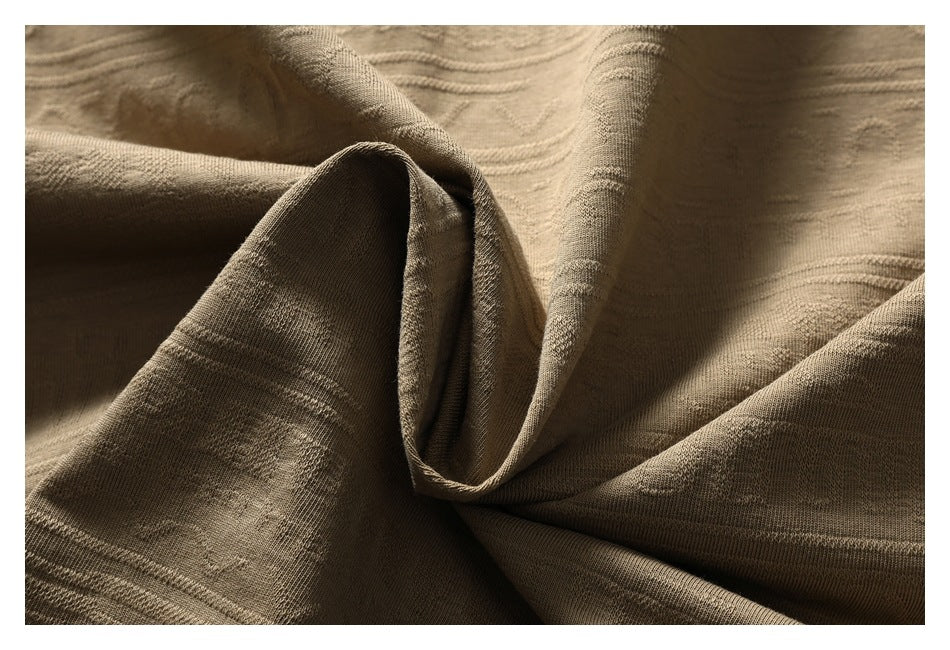 Close-up of taupe-brown fabric draped in soft folds, showing a subtle textured weave.