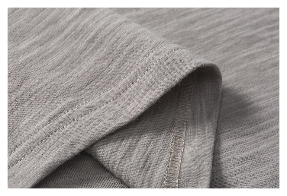 Close-up of light gray fabric folds showing a stitched seam and overlocked edge.