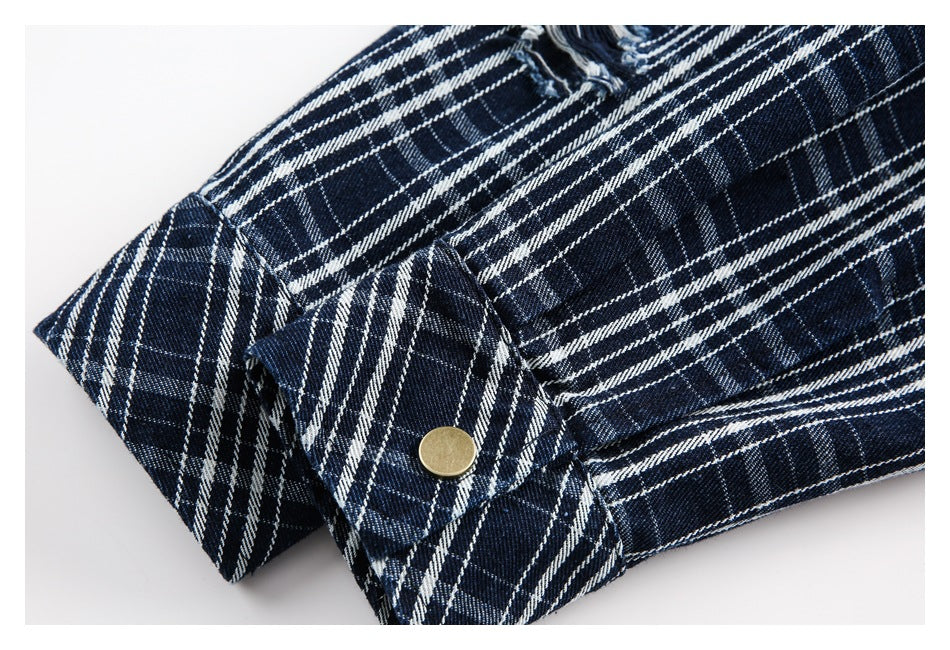 Close-up of a navy-and-white plaid shirt cuff with a brass-colored button and distressed fabric nearby.