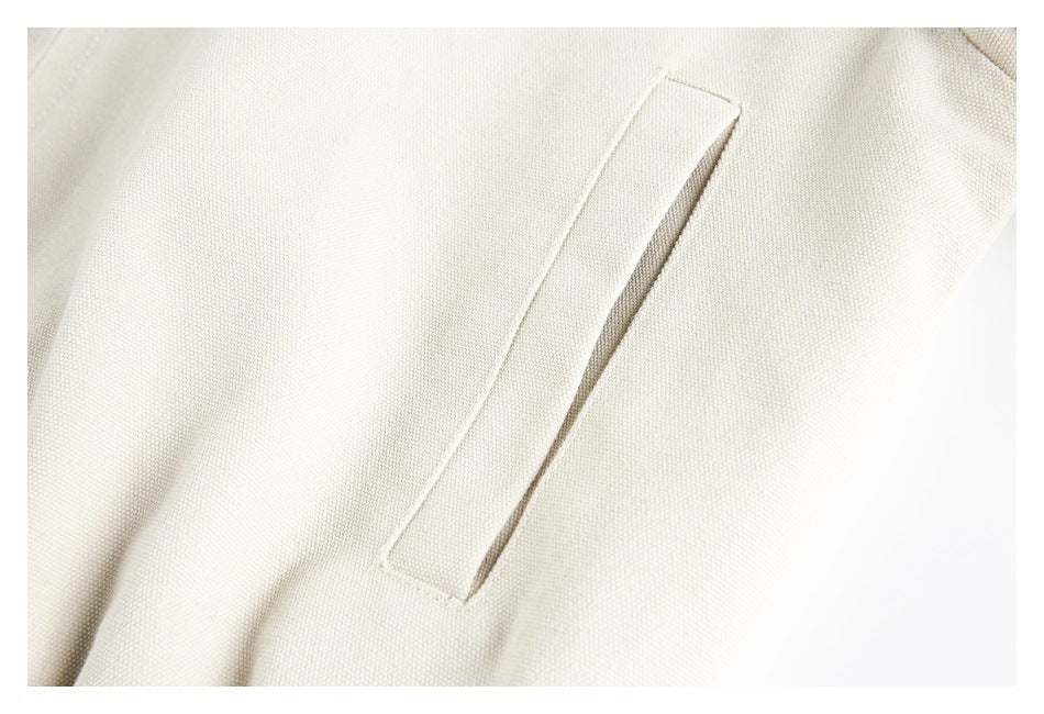 Close-up of a narrow welt pocket on cream textured fabric.