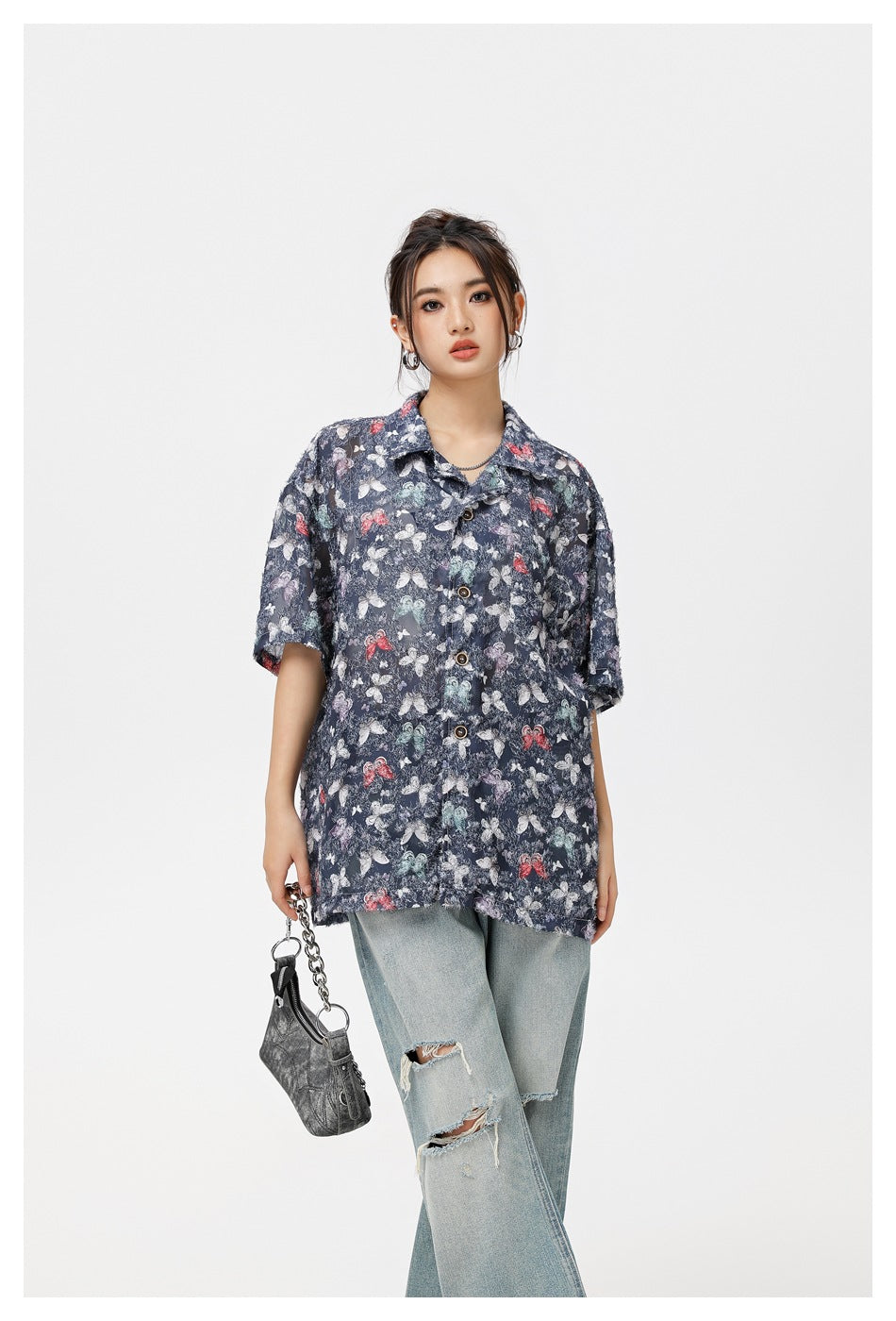 Model wearing a navy short-sleeve button-up shirt with a multicolored butterfly print.