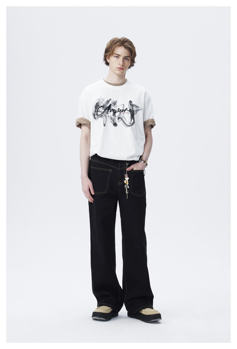 Model wearing white smoke-print T-shirt over a beige tee with black wide-leg jeans, full-length view