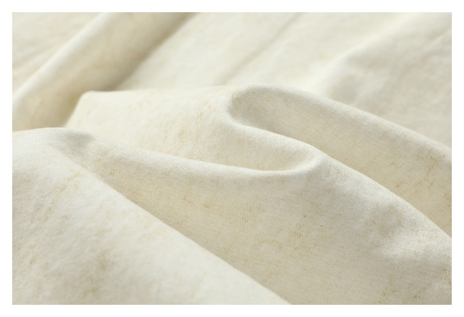 Close-up of softly textured off-white fabric arranged in folds.