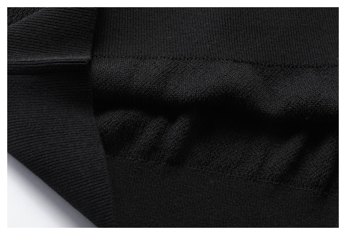 Close-up of black knit fabric and a wide ribbed edge with visible seam transitions.