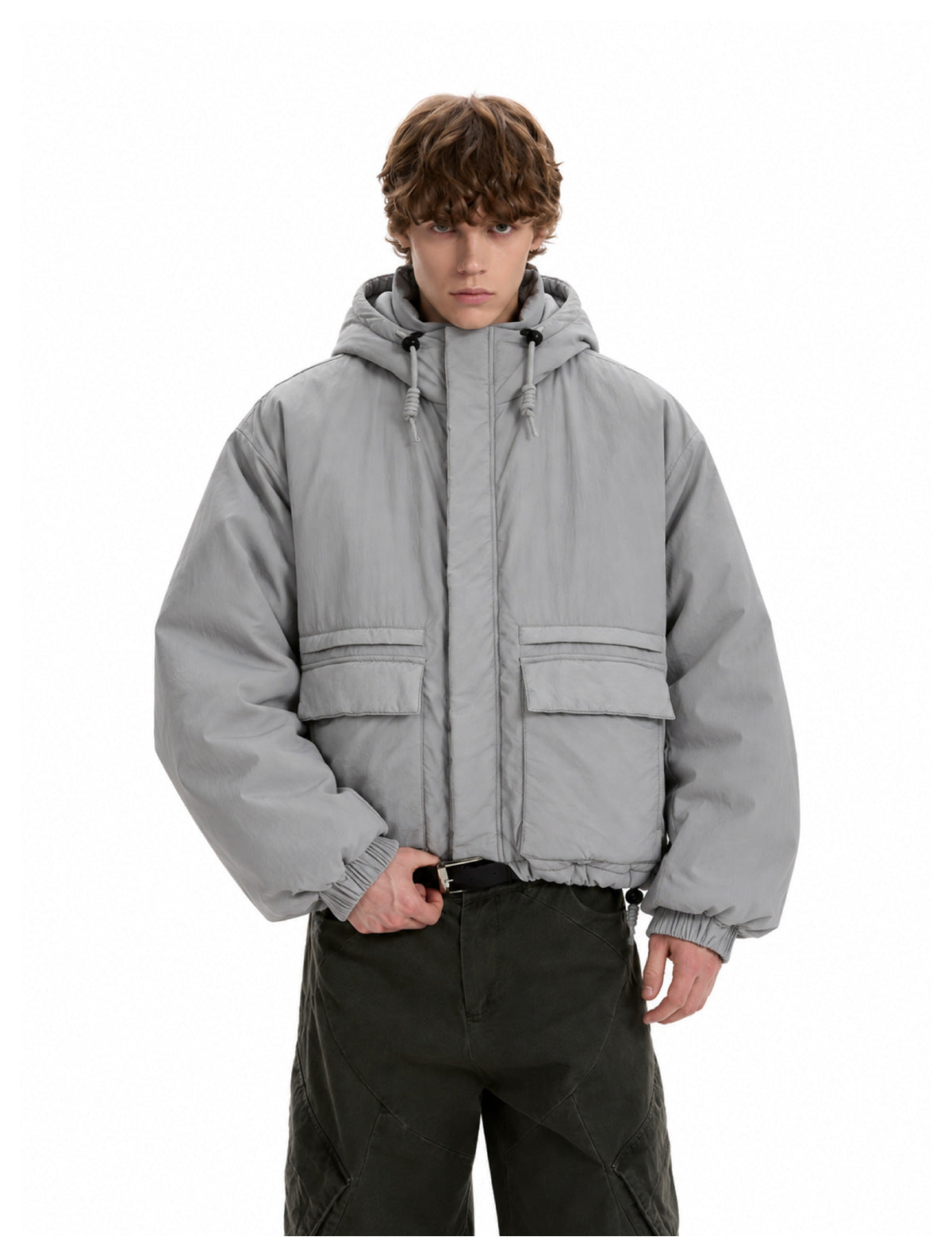 Model wearing a light gray hooded padded jacket with large flap pockets over dark olive pants, front view