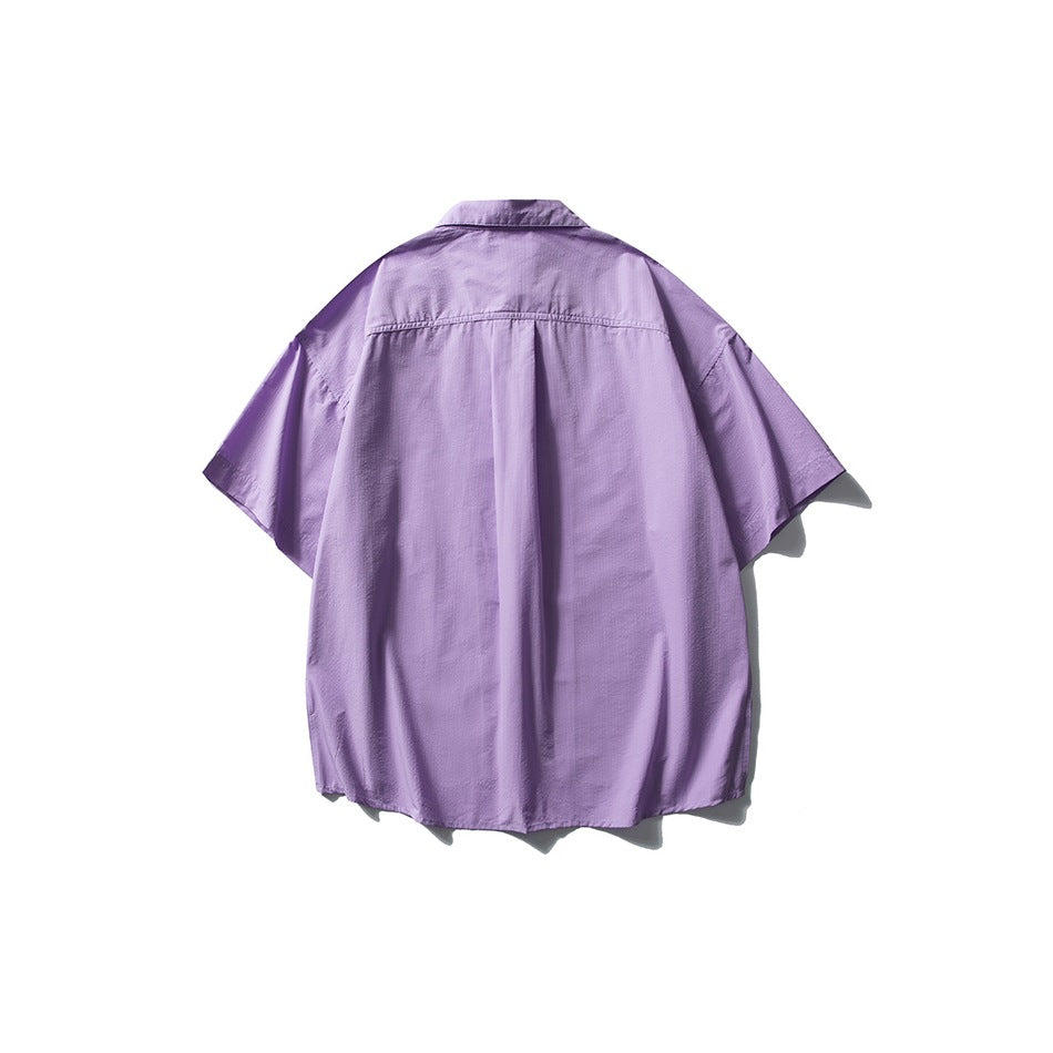Back view of a purple oversized short-sleeve button-up shirt with a center pleat.