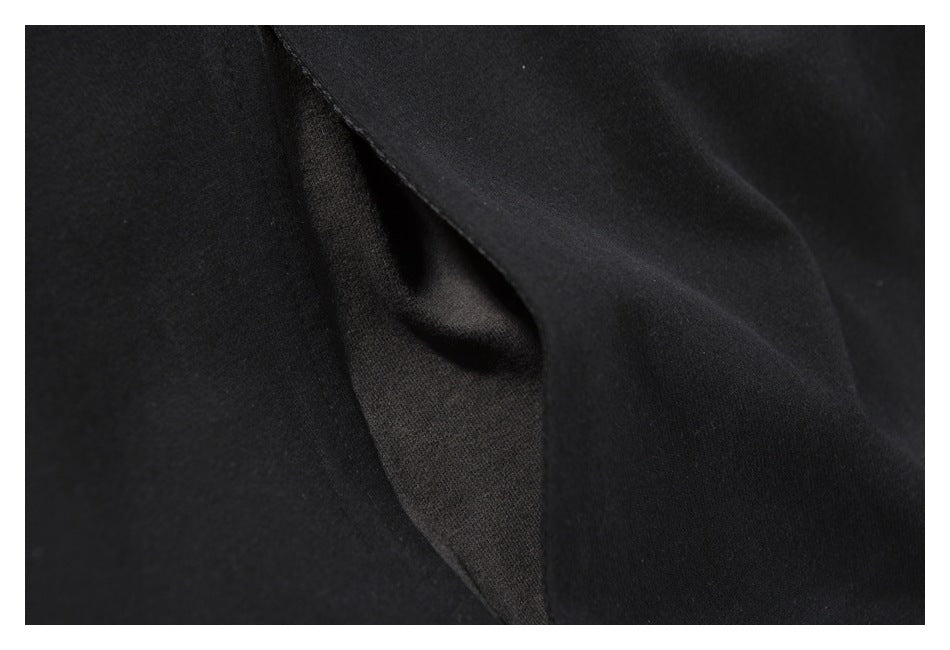 Close-up of a dark fabric opening or fold with black stitching around the edge.