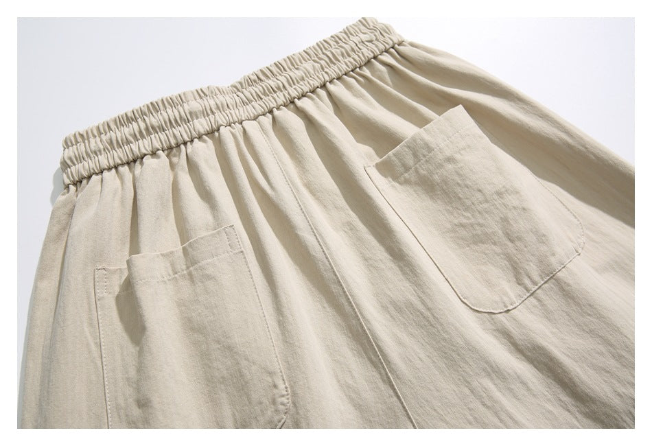 Close-up of beige pants showing a gathered elastic waistband and two patch pockets.