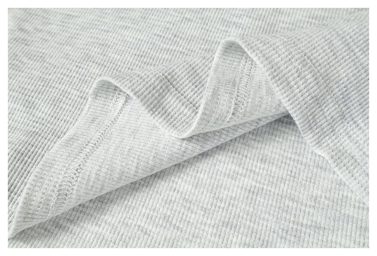 Inside view of light gray ribbed fabric with a folded seam and pale overlock stitching.