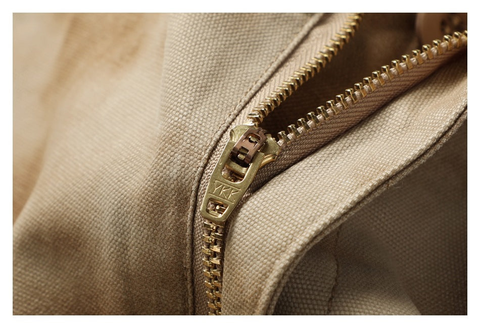Close-up of the brass zipper and textured tan fabric on the pants.