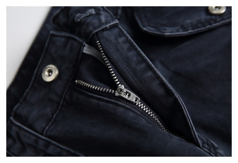 Close-up of dark charcoal trousers showing an open zipper fly and metal button.