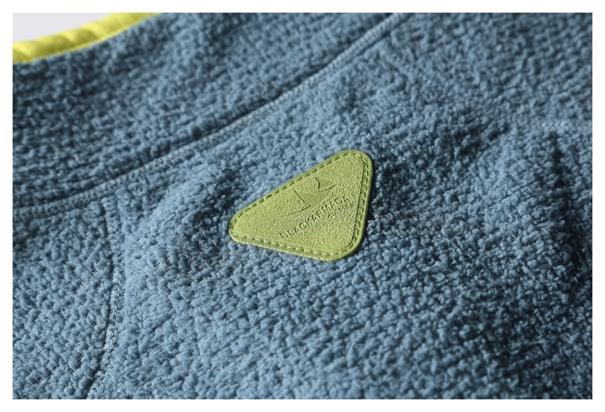 Close-up of blue textured fleece with a stitched lime-green triangular patch.
