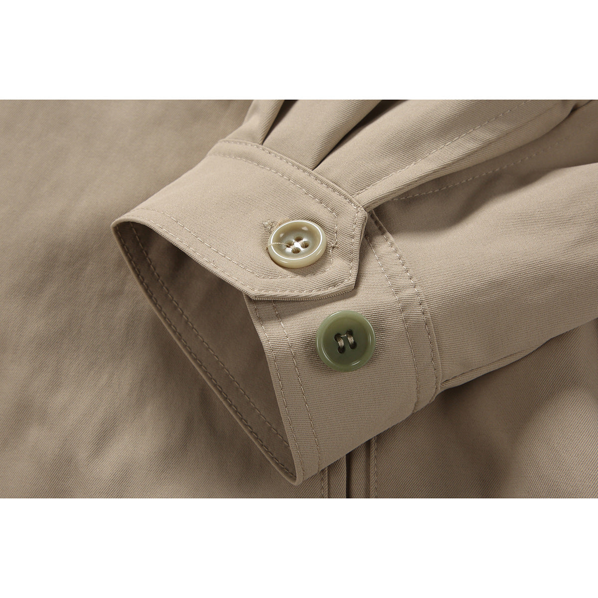 Close-up of a beige jacket cuff with two contrasting buttons and visible stitching.