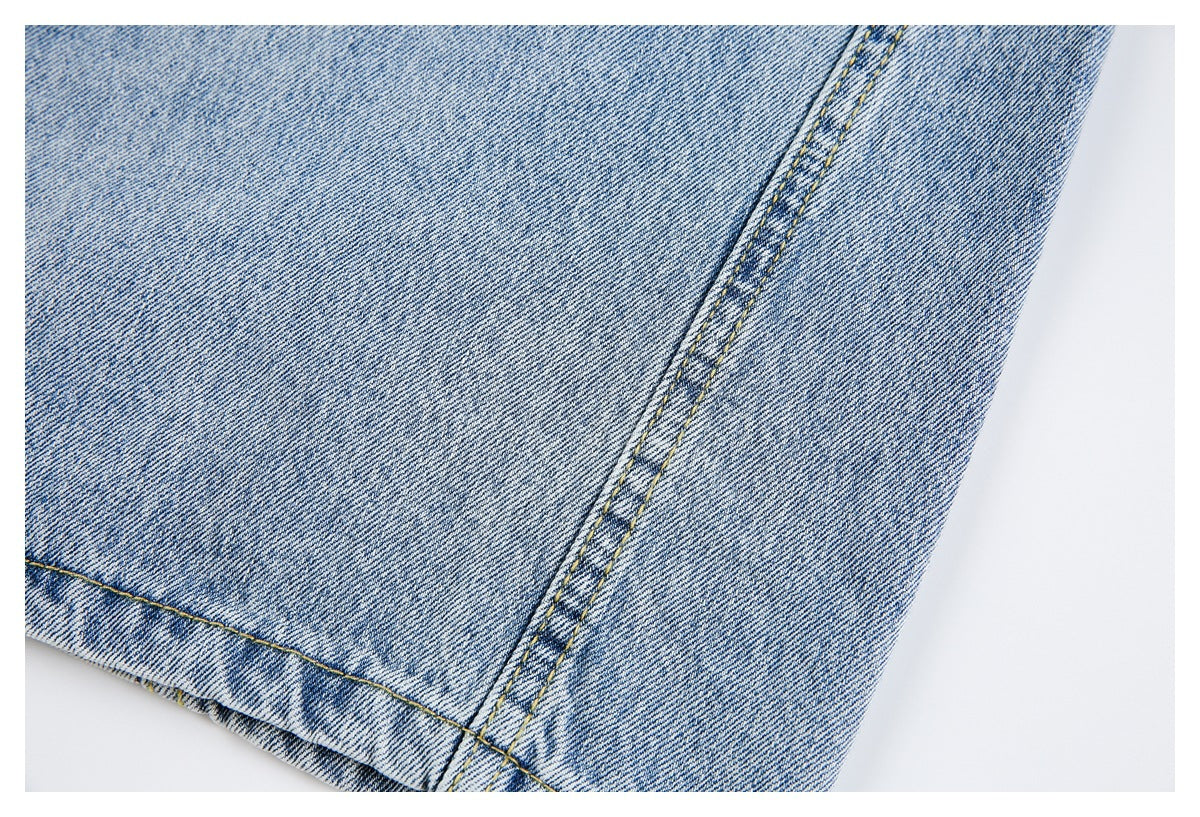 Close-up of light blue denim with a double-stitched seam and folded hem.