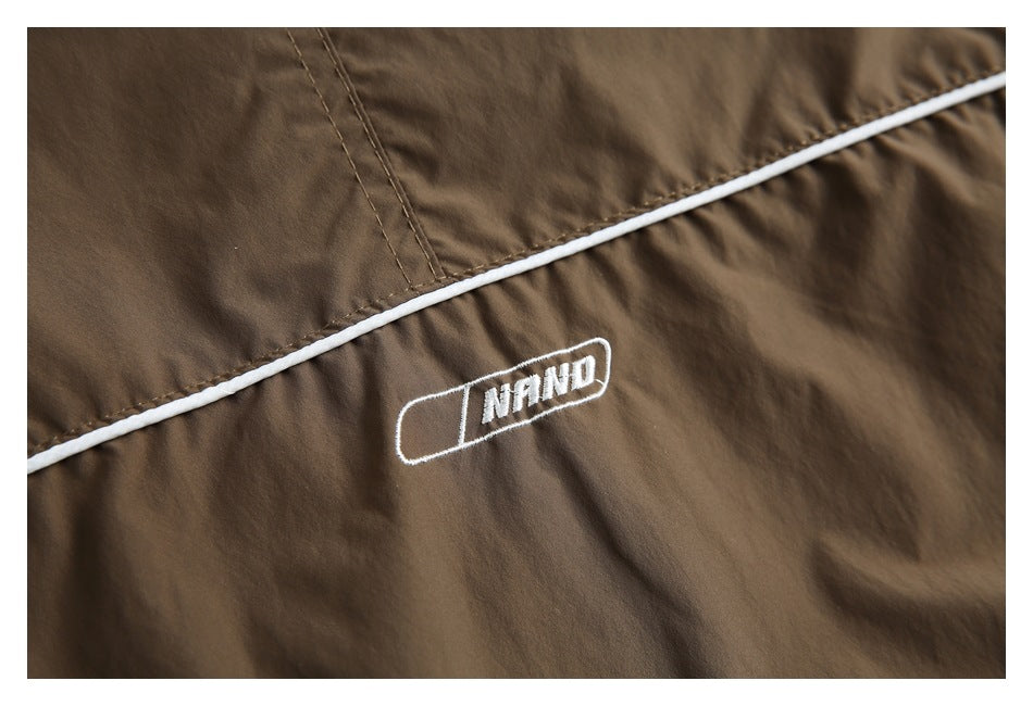 Close-up of a white embroidered emblem and piping on brown jacket fabric.