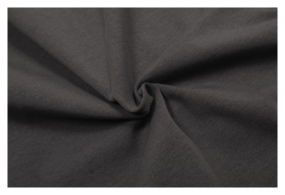 Close-up of dark charcoal fabric draped into soft folds, showing its surface texture.