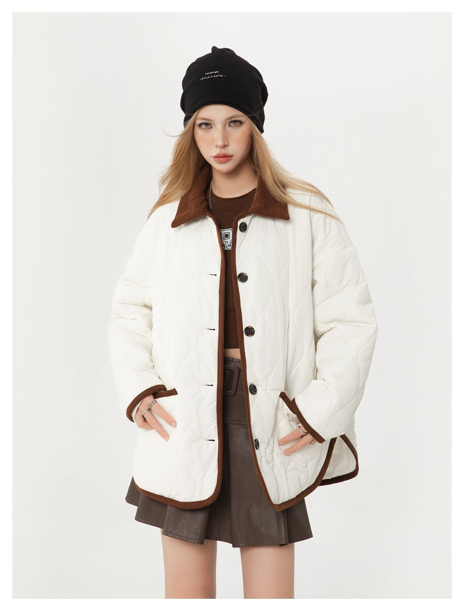 Model wearing an ivory quilted jacket with brown collar and trim, dark buttons, and a black beanie.