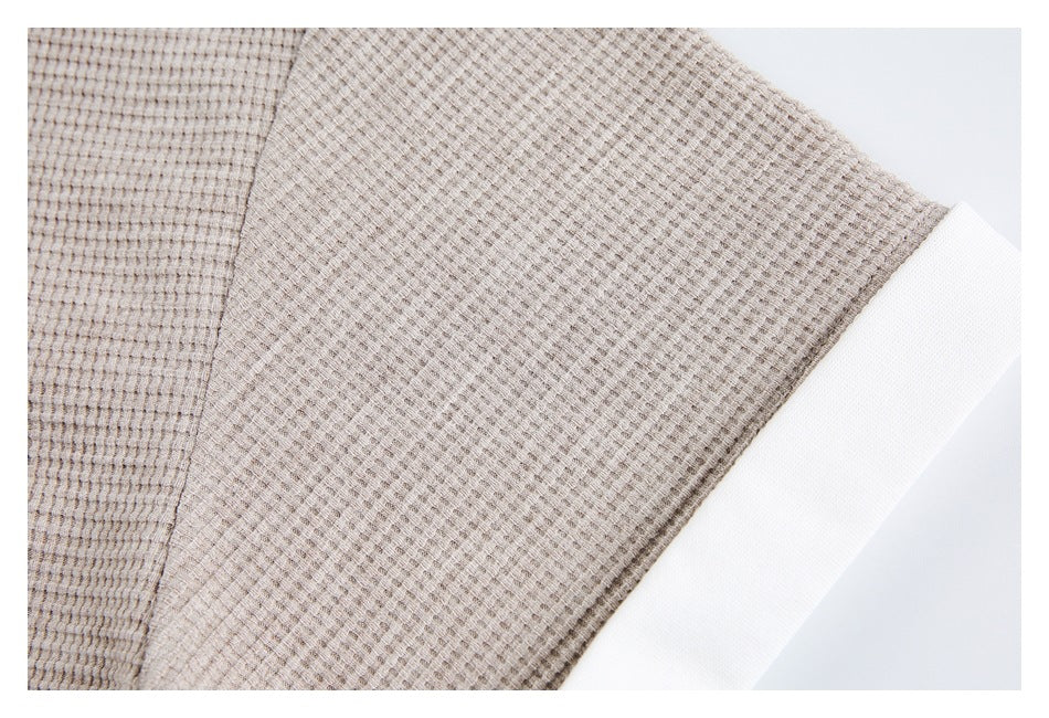 Close-up of beige-gray fabric with a small waffle-like texture and a white edge.