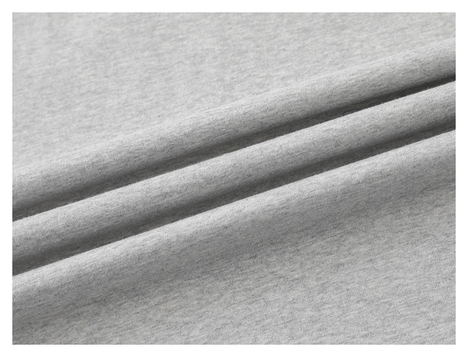 Close-up of light gray heather T-shirt fabric arranged in soft folds.