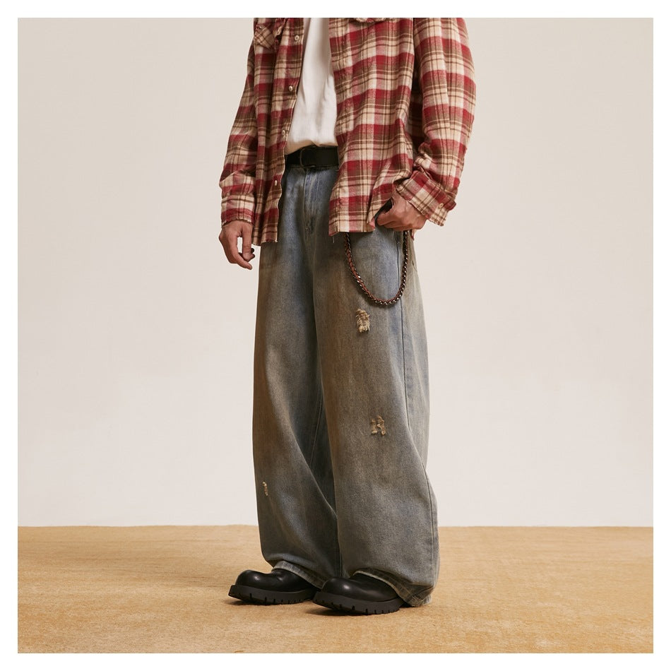 Model wearing loose gray washed jeans with distressed patches, shown at a front-side angle.