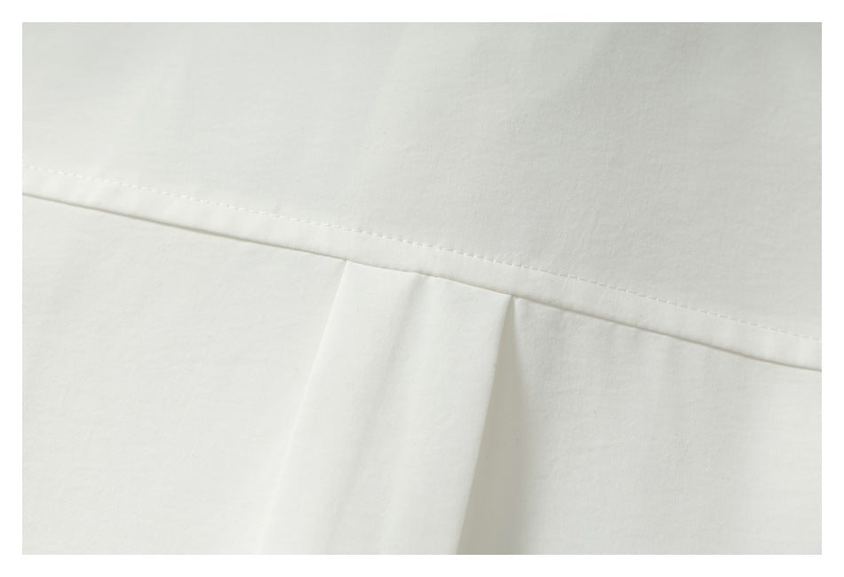 Close-up of an off-white garment's stitched seam and fabric fold.