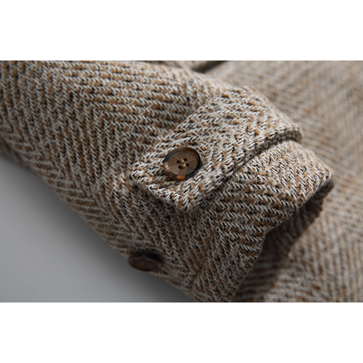 Close-up of the beige patterned coat's cuff tab and brown button.