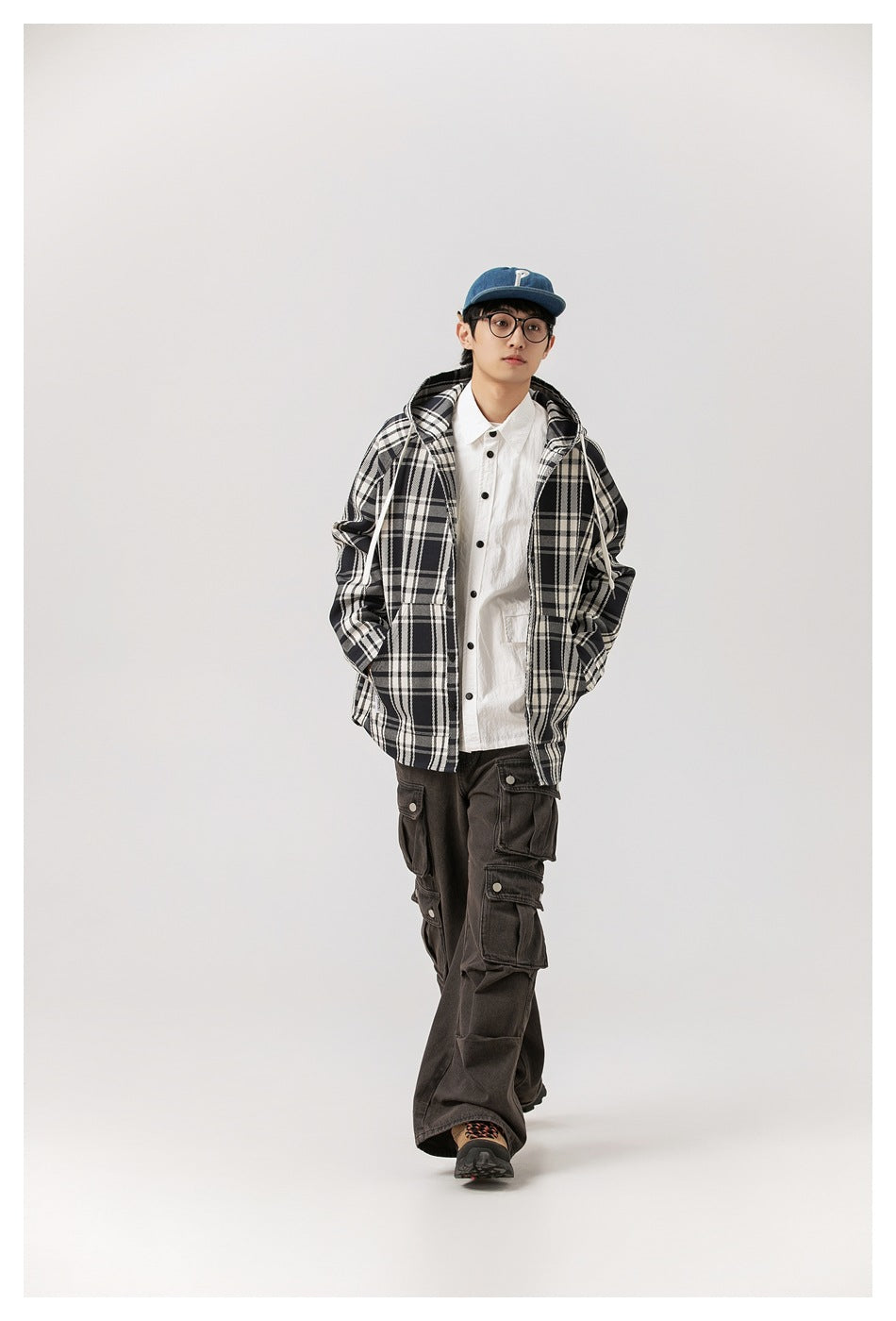 Model wearing the plaid hooded jacket open over a white shirt with a denim cap and brown cargo pants