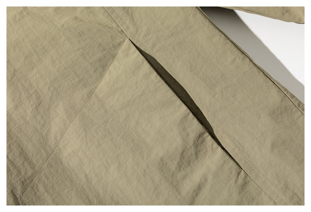 Close-up of a khaki jacket's stitched panel and diagonal opening.