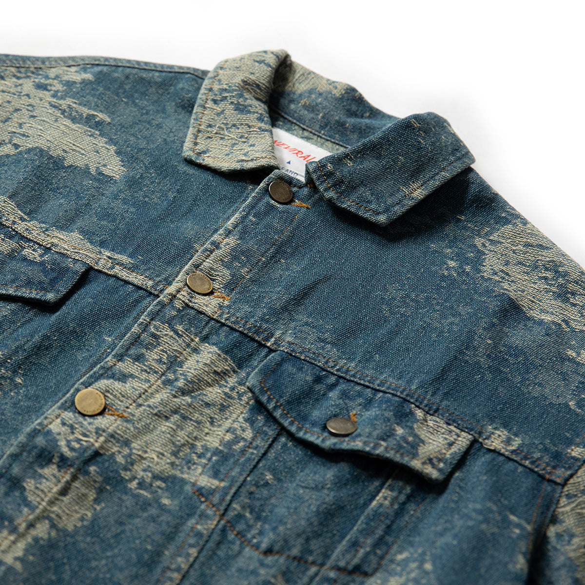 Close-up of a blue distressed denim jacket showing its collar, button placket, and flap chest pockets.