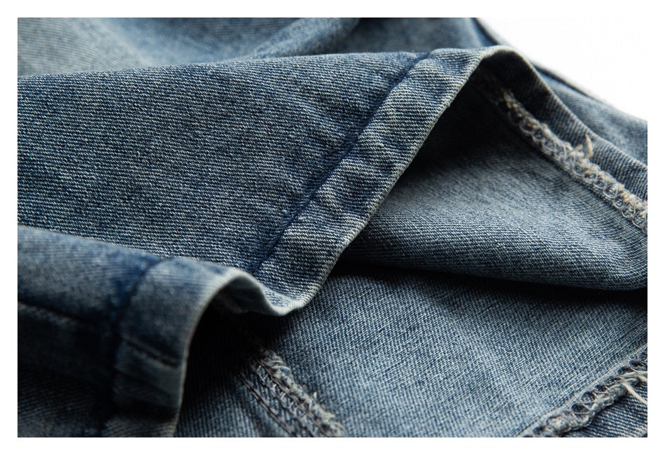 Close-up of a folded denim hem showing the fabric edge and interior overlock stitching.