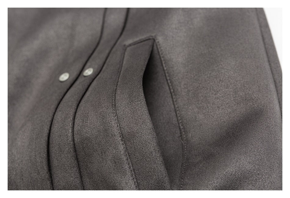 Close-up of a charcoal gray garment showing a curved seam, overlapping panel, and two light-colored snaps.