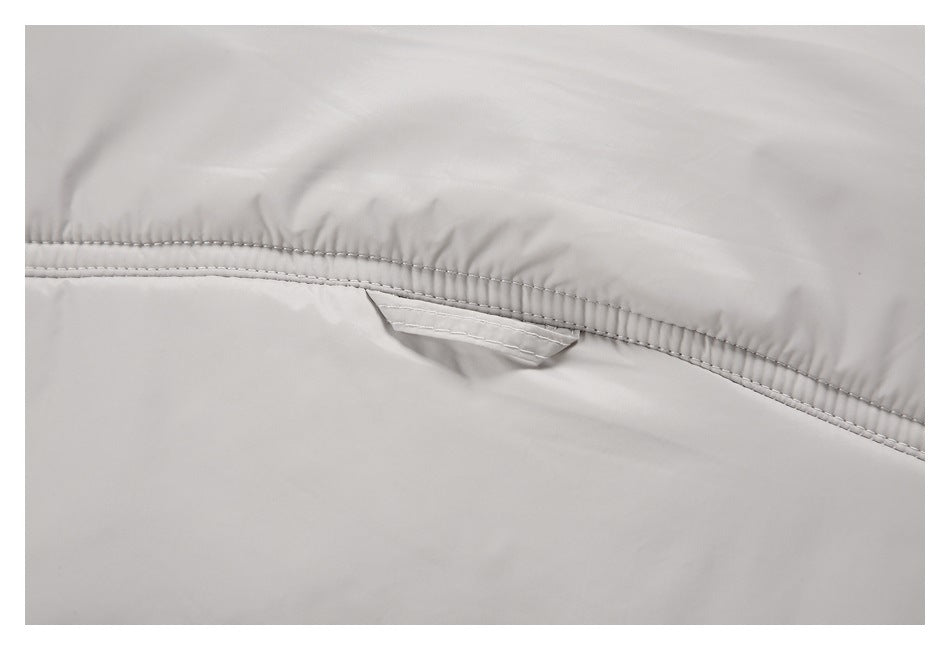 Close-up of a small fabric tab beneath the stitched yoke on a light gray jacket.