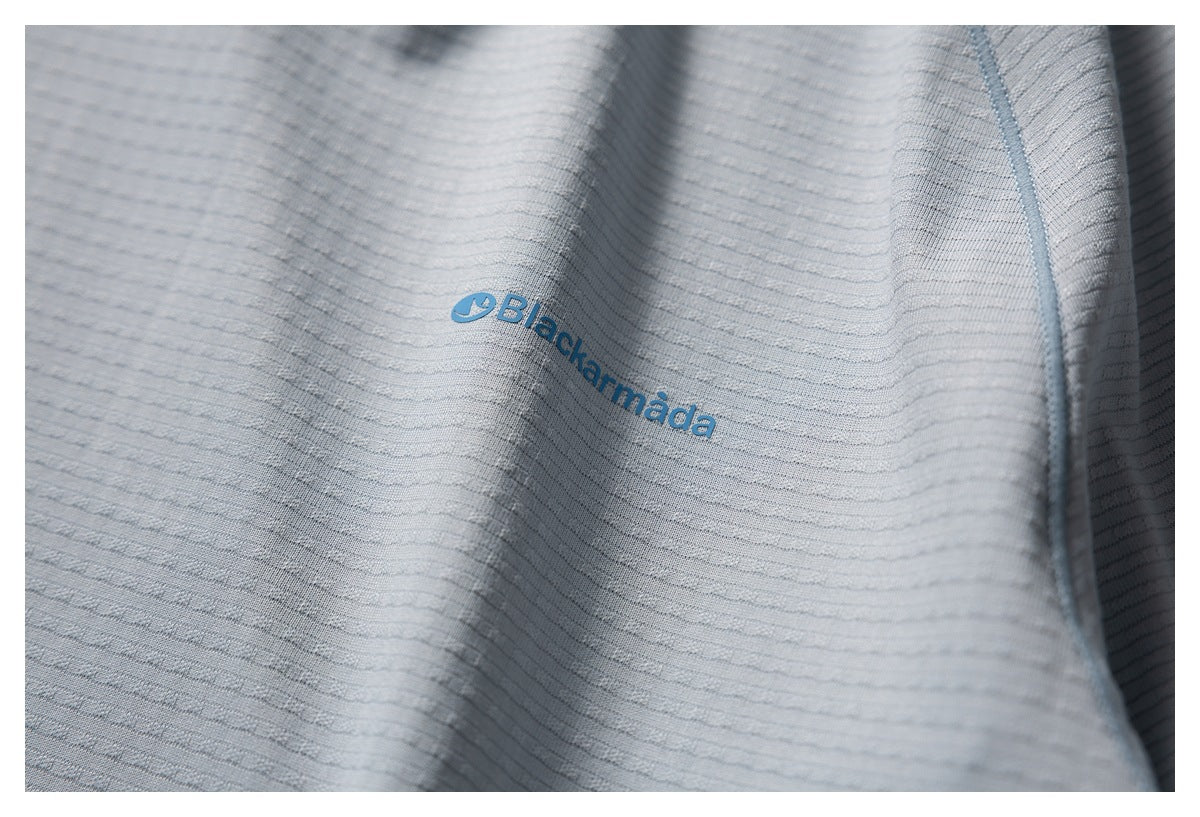 Close-up of a blue Black... logo printed on the textured gray-blue shirt fabric.