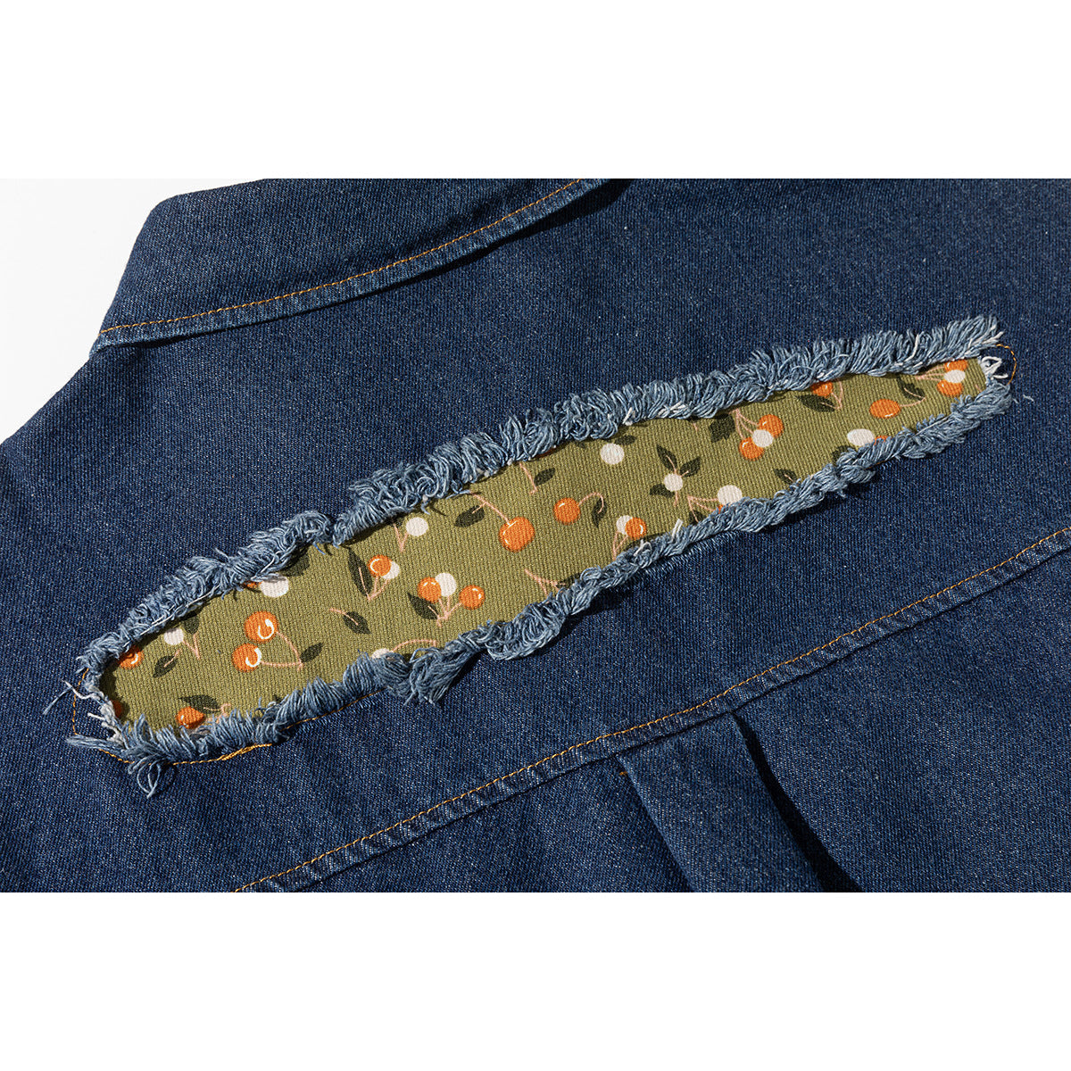 Close-up of a frayed green floral fabric insert on the back of a dark blue denim shirt.