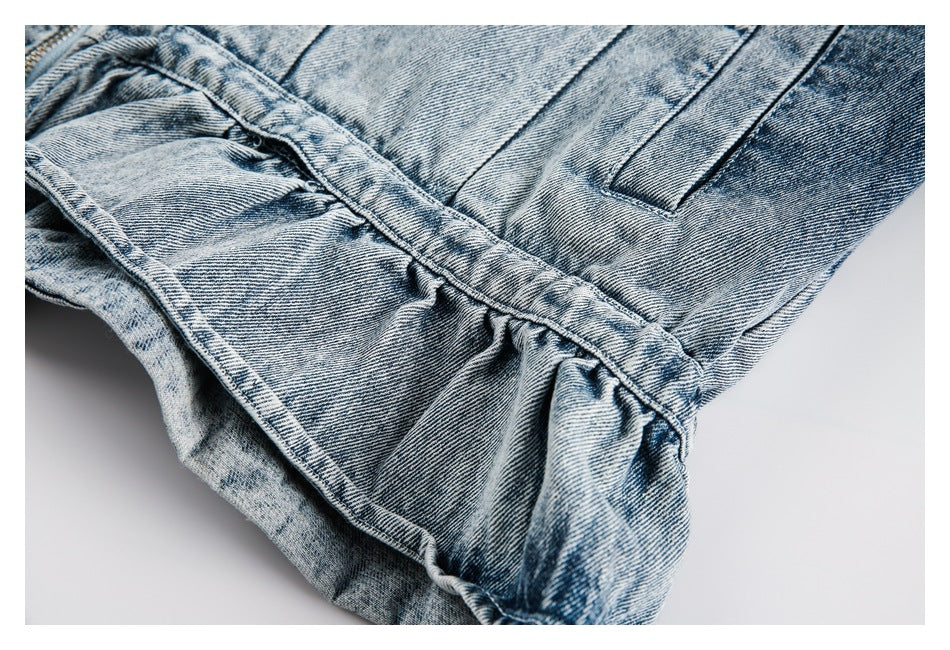 Close-up of a gathered denim waistband and slanted pocket on faded blue pants.