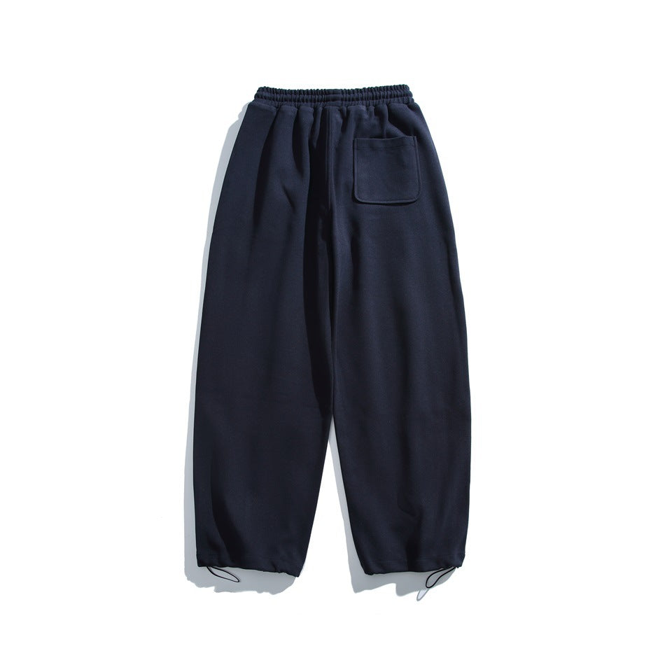 Navy relaxed-fit pants with an elastic drawstring waist, one patch pocket, and gathered ankle cuffs, shown flat.