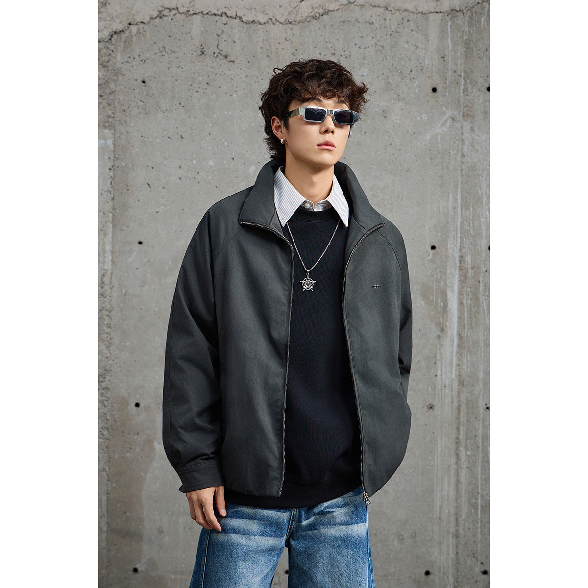 Front view of a person wearing a charcoal zip-up jacket with a high collar and small chest detail.