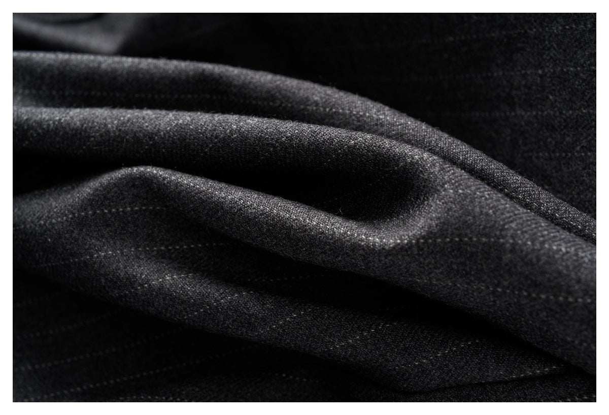 Macro view of charcoal gray trouser fabric gathered into deep folds.