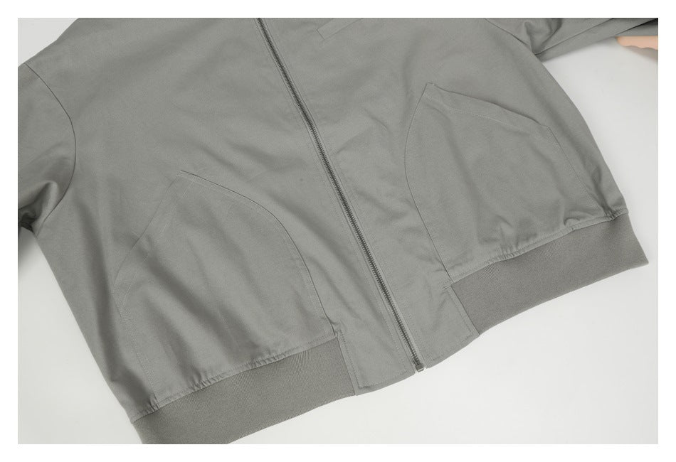 Close view of a gray zip-front jacket with two angled pockets and a ribbed hem.