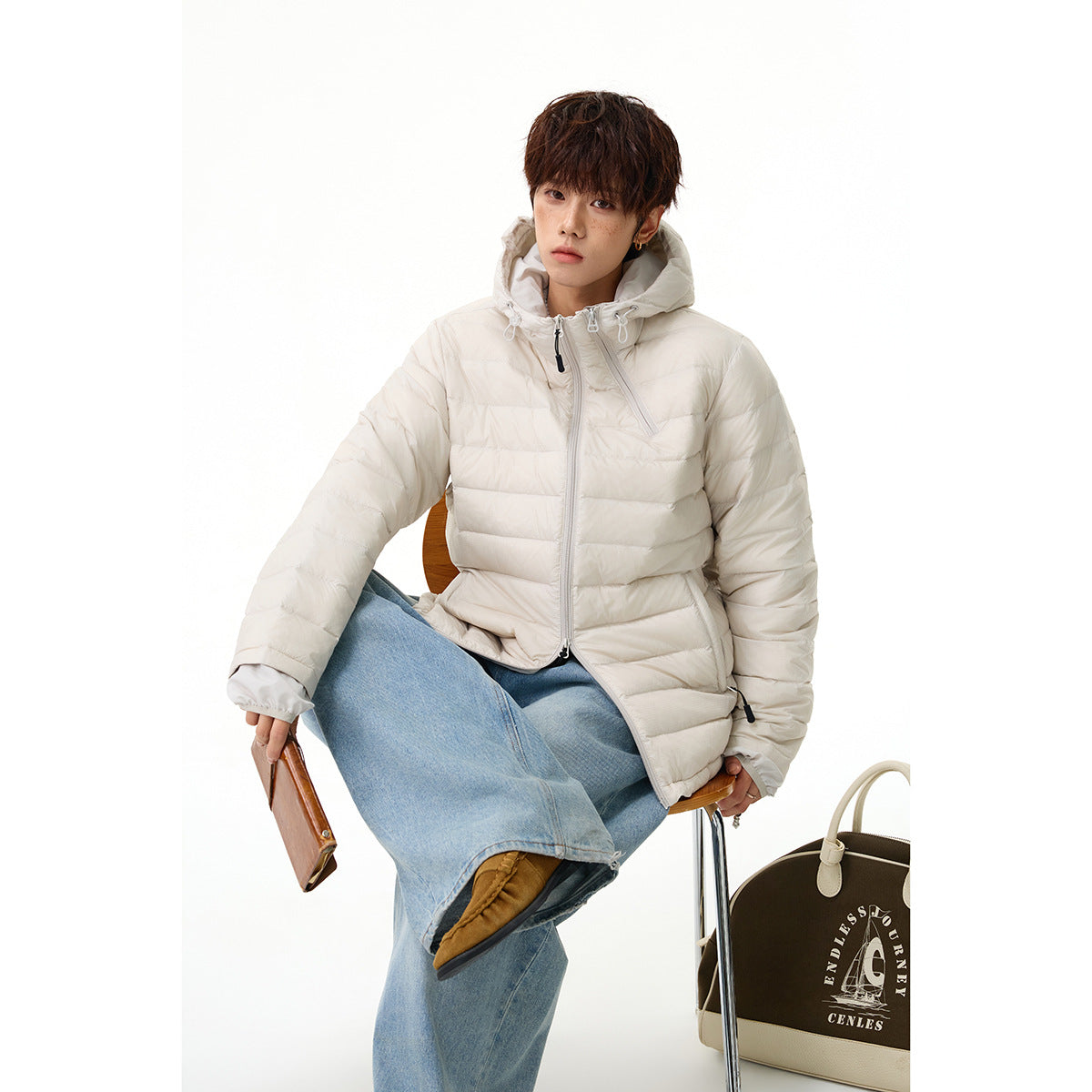 Model seated in an ivory hooded puffer jacket with light blue wide-leg jeans.