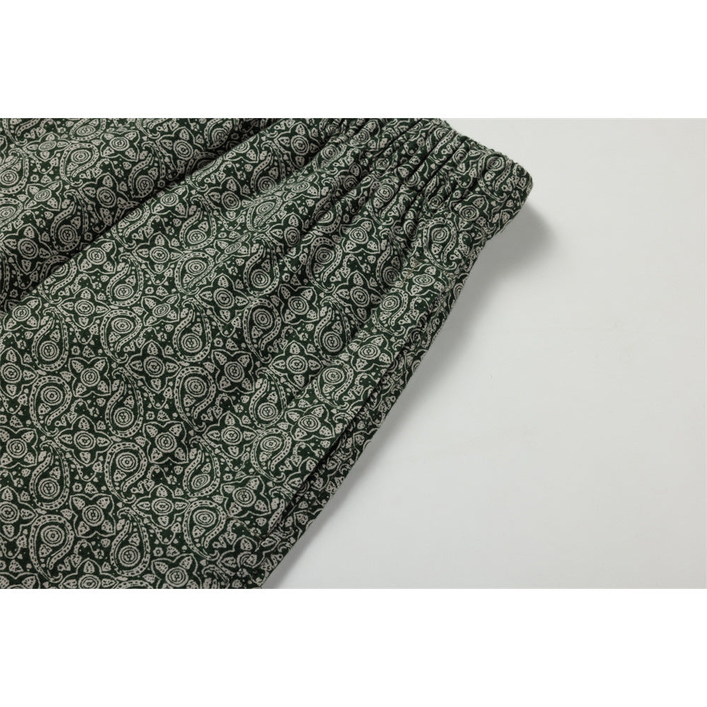 Close-up of the gathered waistband and front seam on dark green paisley-print pants.